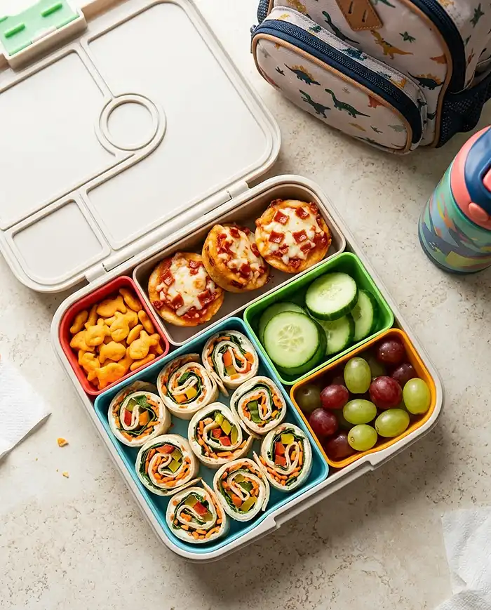 Gluten free snacks for kids packed in a lunch box with veggie pinwheels, pizza muffins, and fish crackers